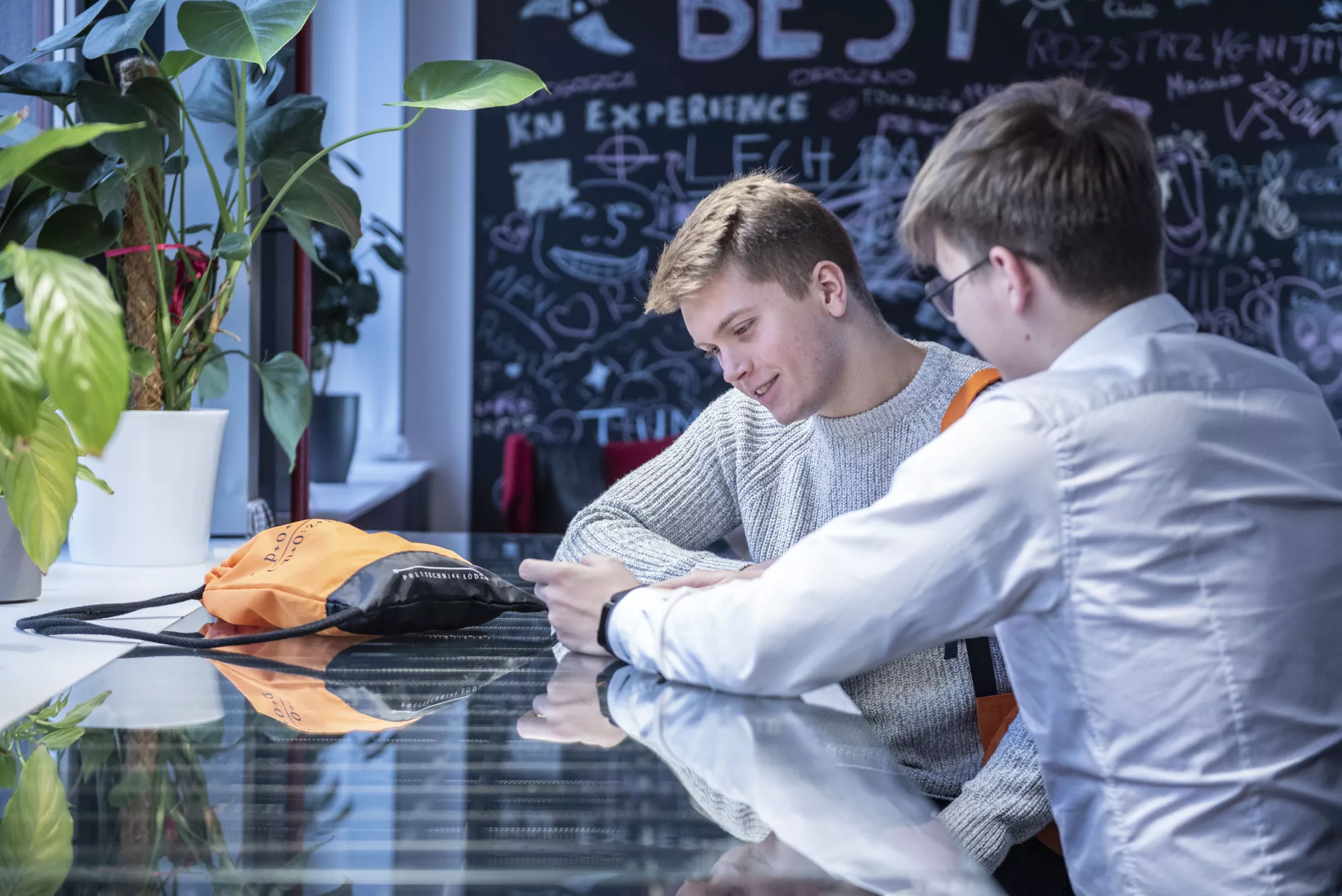 Studenci rozmawiają w ładnej sali.