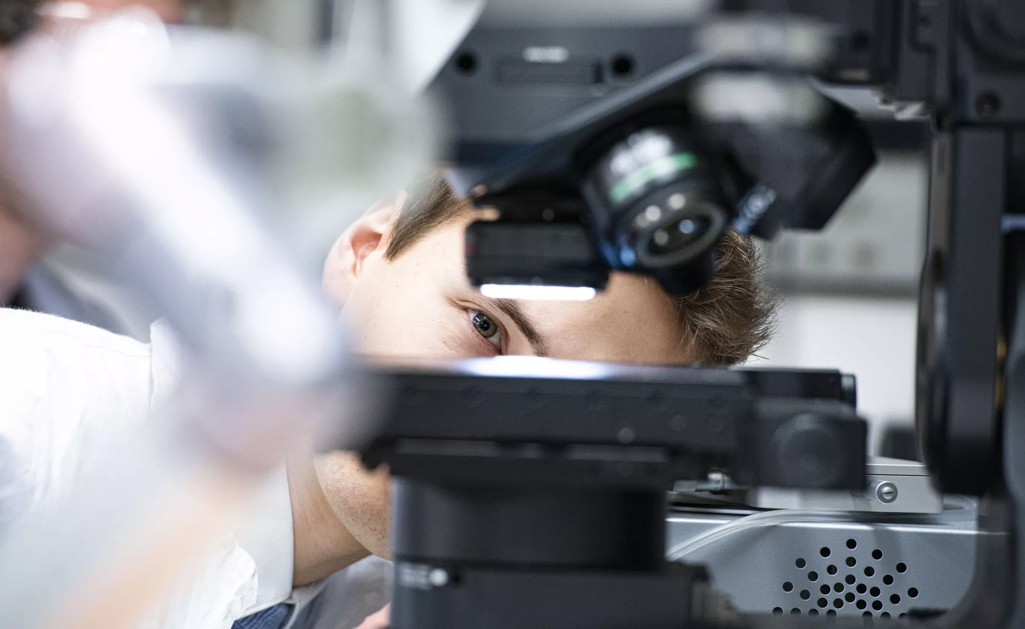 Mężczyzna zagląda pod mikroskop.