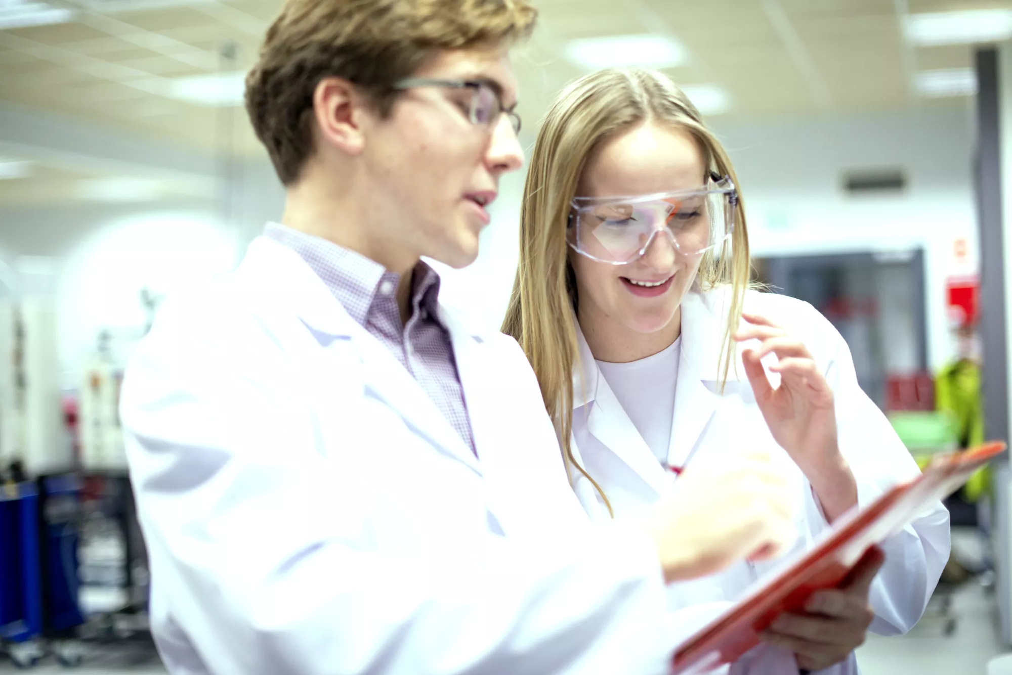 Studenci w fartuchach prowadzą eksperymenty chemiczne.