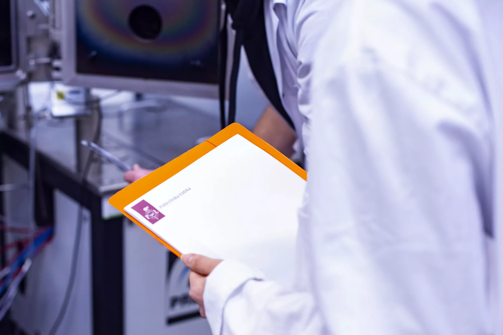 Student z teczką PŁ w laboratorium.