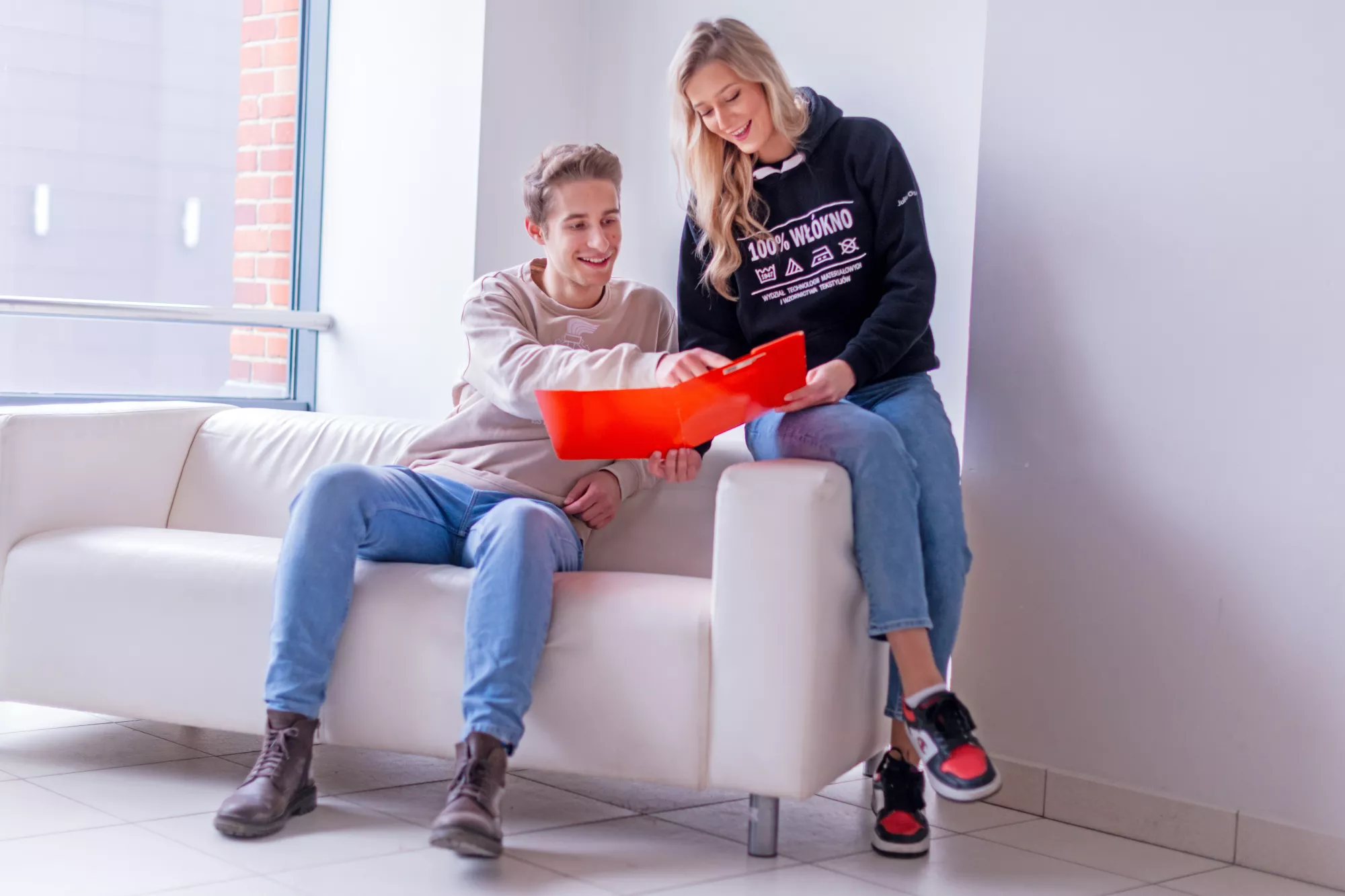 Dwoje studentów rozmawia przy pomarańczowej teczce.