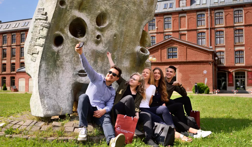 Studenci robią sobie zdjęcie przed budynkiem PŁ.